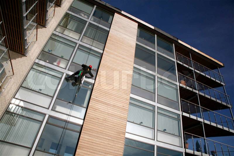 Climber on job as windows cleaner in a quiet new apartment building by the waterfront of Nyborg, Denmark, stock photo