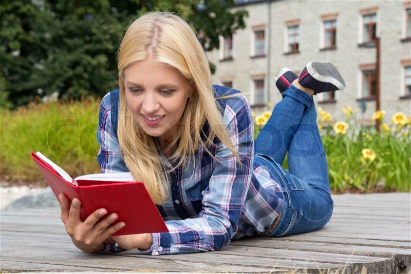 Young beautiful woman reading book in park, stock photo