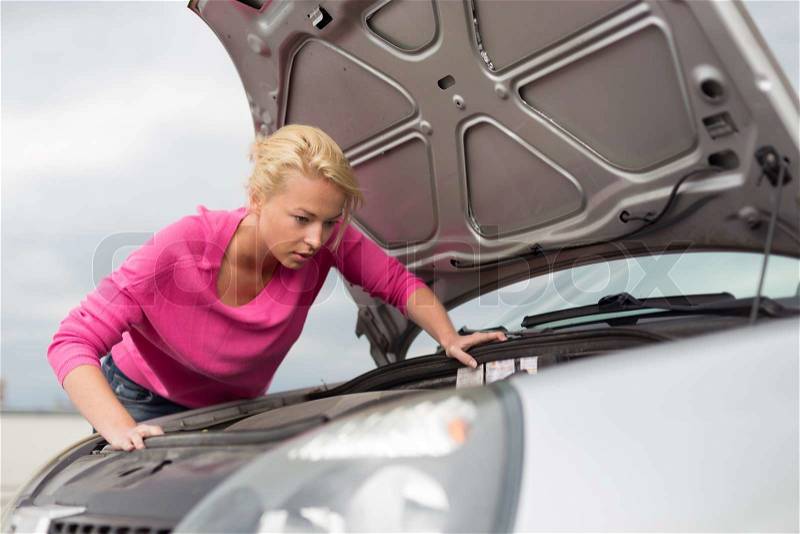 Self-sufficient confident modern young woman inspecting broken car engine, stock photo