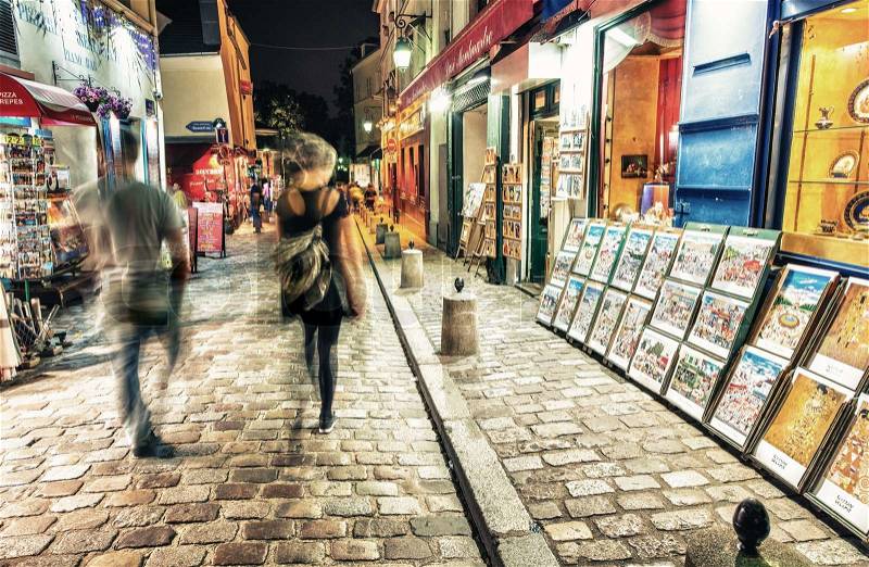 PARIS - JUNE 23, 2014: Tourists and locals walk in Montmartre streets at night. Montmartre attracted many famous modern painters in the early 20th century, stock photo
