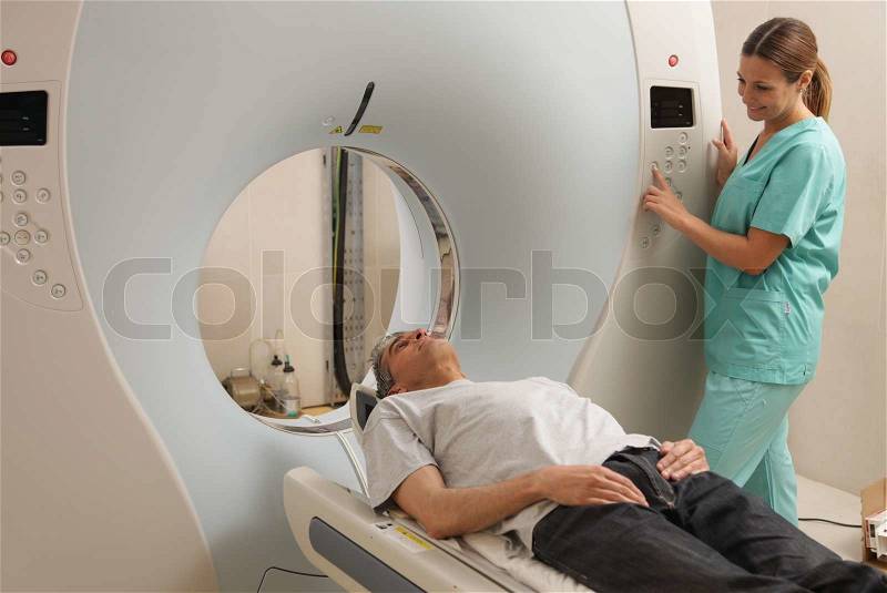 Young female doctor examining man in 40s with CT scanner. Computerised tomography, stock photo