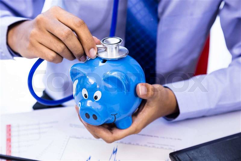 Businessman use stethoscope with piggy bank for financial health check concept, stock photo