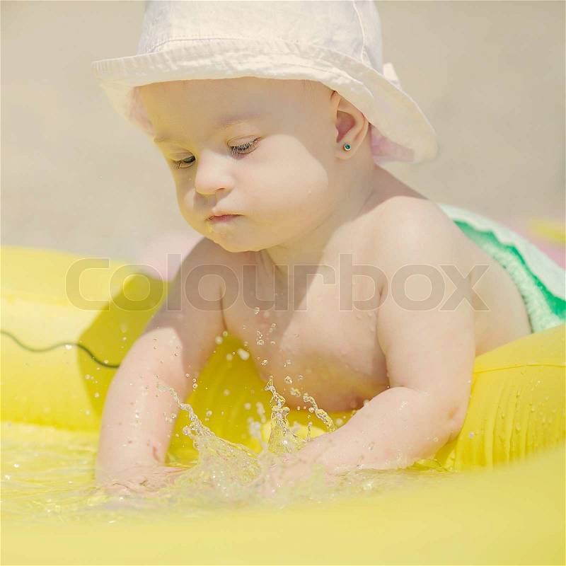 Cheerful little baby girl with Downs Syndrome playing in the pool, stock photo