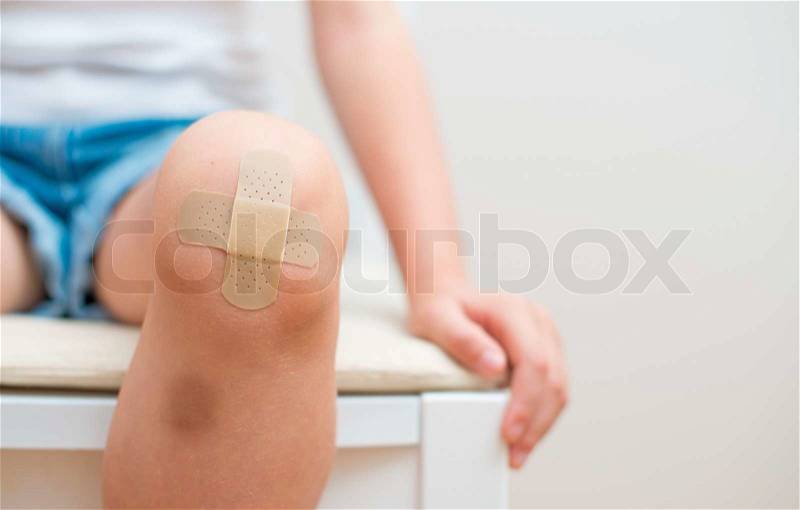 Child knee with an adhesive bandage and bruise, stock photo