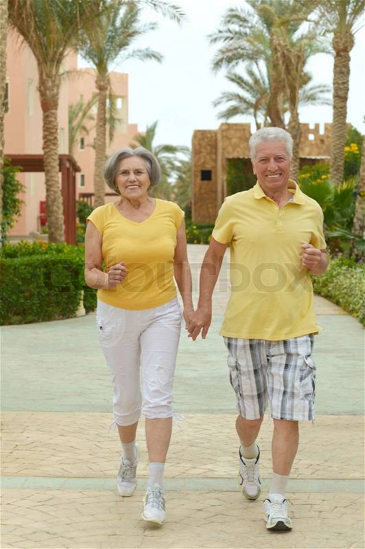 Senior couple run at tropic hotel resort, stock photo