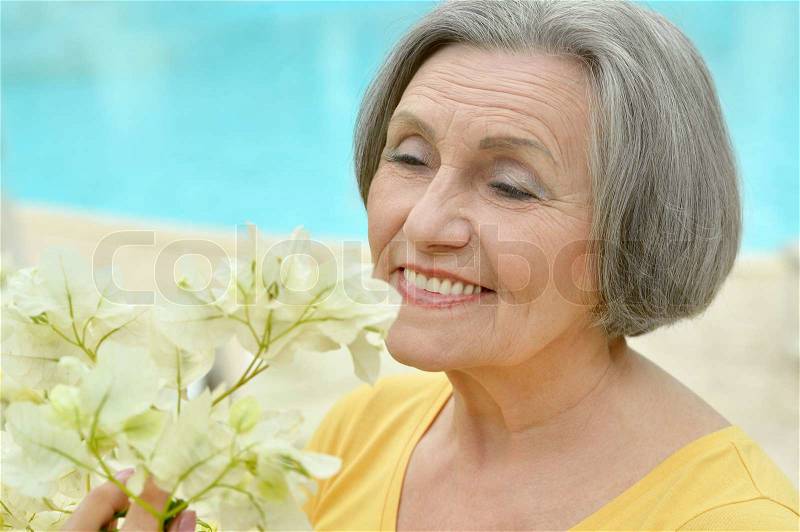 Cheerful cute retired woman posing with flowers, stock photo
