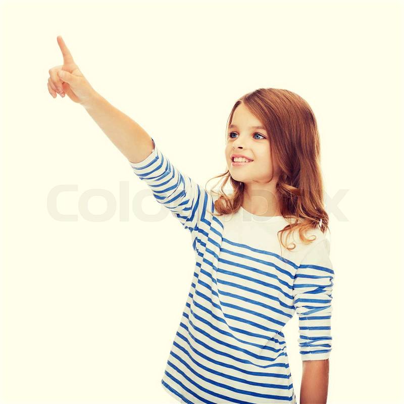Education, school and virtual screen concept - cute little girl pointing in the air or virtual screen, stock photo