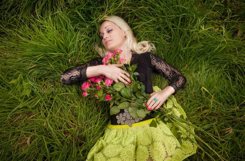 Closeup portrait of woman with roses sleeping at field, stock photo