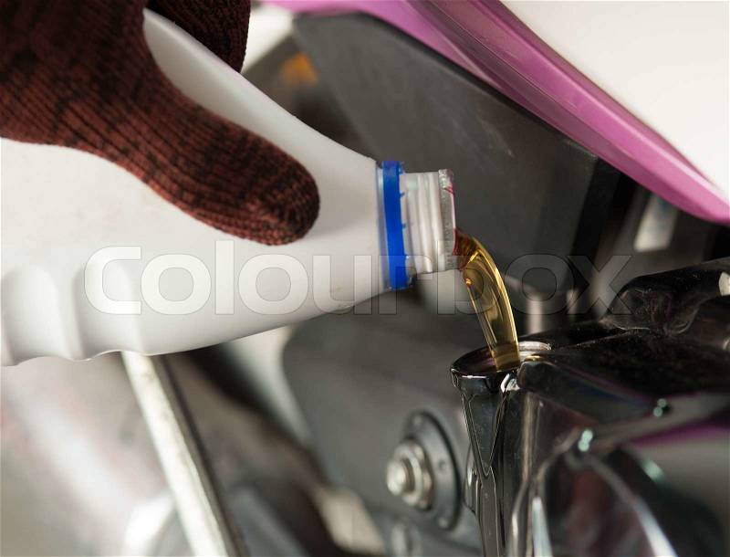 Fill oil to the engine after driving motorcycle, stock photo
