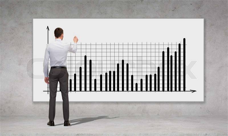 Business, development and office people concept - businessman with marker drawing chart over concrete wall background from back, stock photo