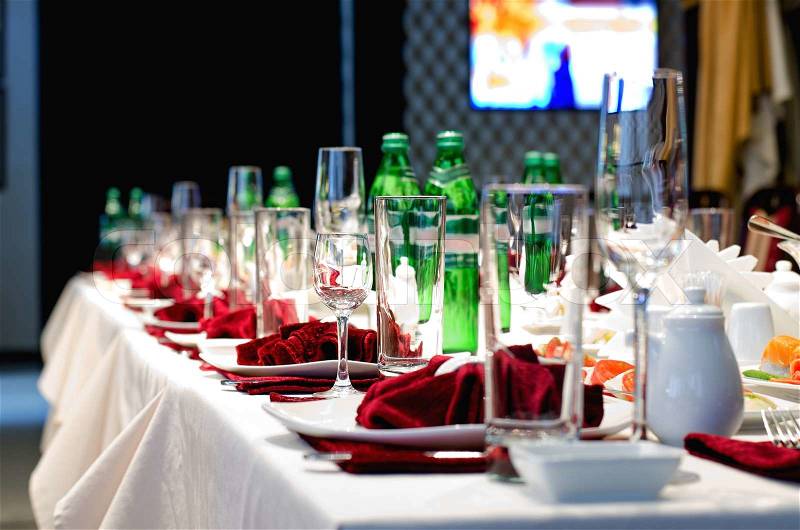 Formal stylish setting on a dinner table with elegant glassware and red linen for a party or celebration of a special event, stock photo