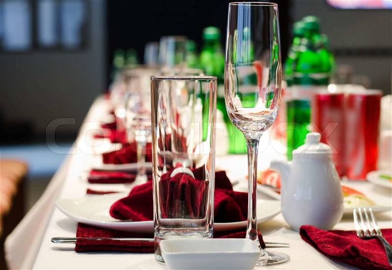 Formal stylish setting on a dinner table with elegant glassware and red linen for a party or celebration of a special event, stock photo