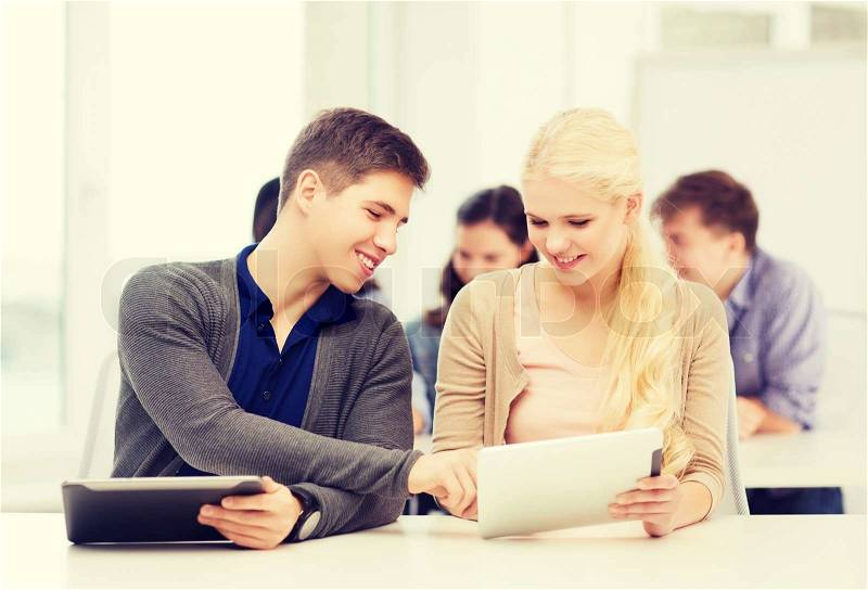 Education, technology and internet - two smiling students looking at tablet pc in lecture at school, stock photo