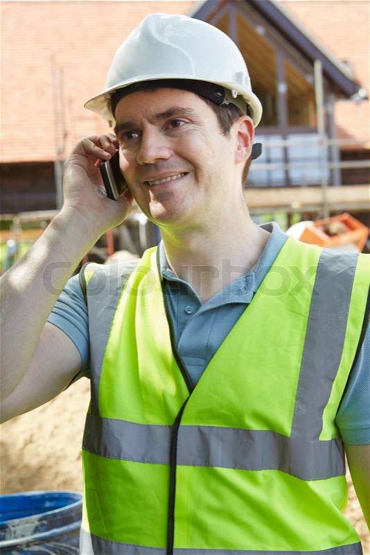 Construction Worker On Building Site Using Mobile Phone, stock photo