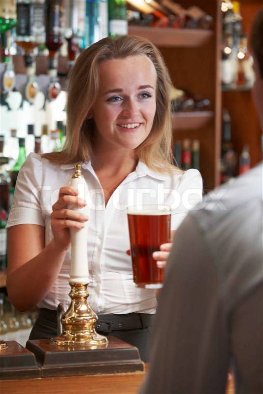 Female Bartender Serving Drink To Male Customer, stock photo