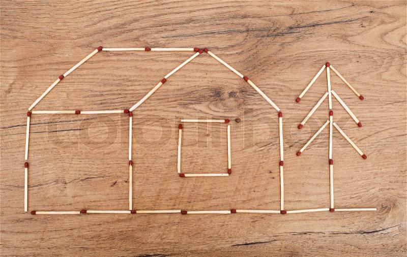 House made from matches on wooden tabletop, stock photo