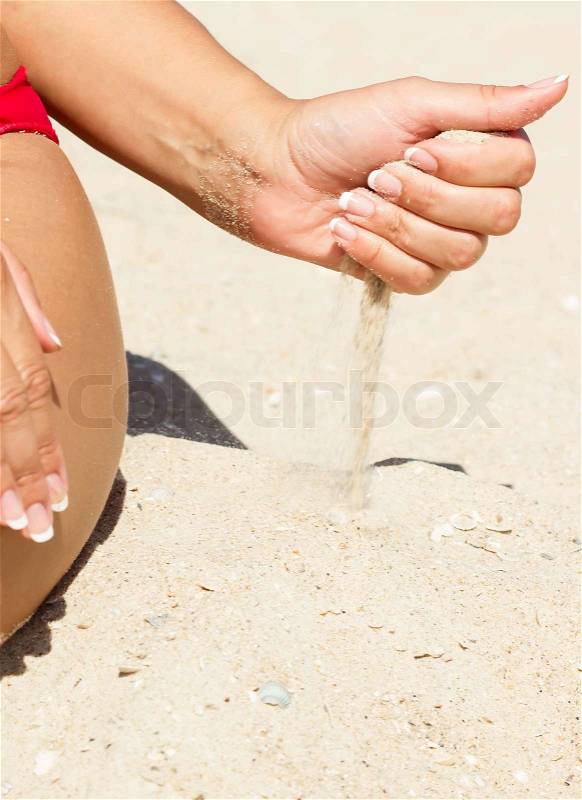 Woman playing with sand on the beach, stock photo