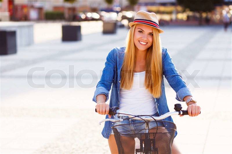 Young stylish woman with a bicycle in a city street, stock photo