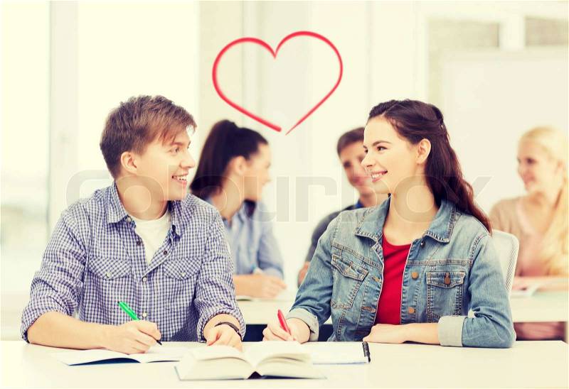 Education, school and people concept - two teenagers with notebooks and book looking at each other at school, stock photo