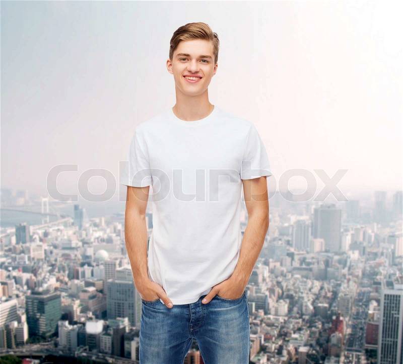 Advertising and people concept - smiling young man in blank white t-shirt over city background, stock photo