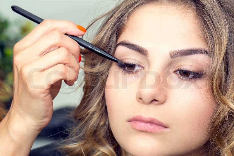 Makeup makes a girl in a beauty salon, stock photo