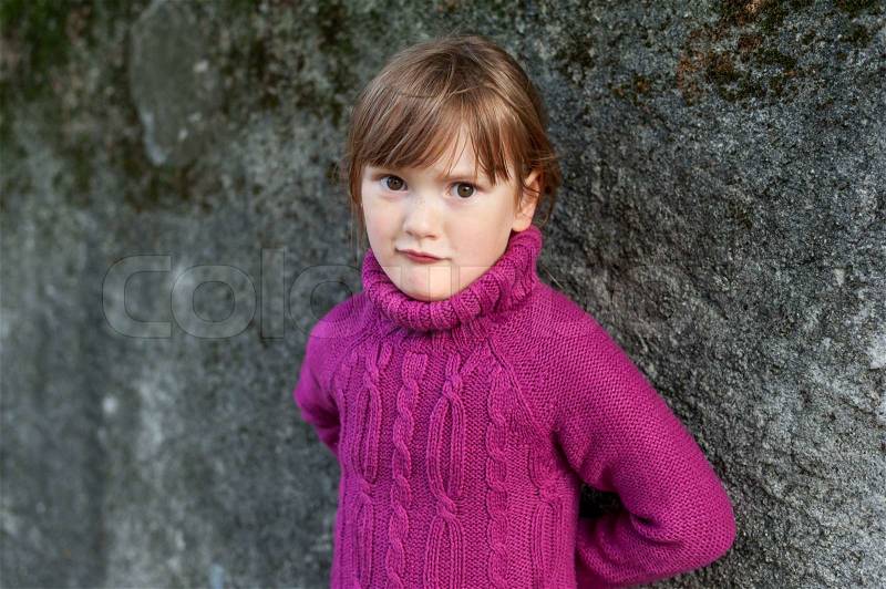 Portrait of a beautiful little girl with freckles in a fuchsia sweater, stock photo