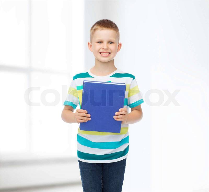 Education, childhood and school concept - smiling little student boy with blue book over white room background, stock photo