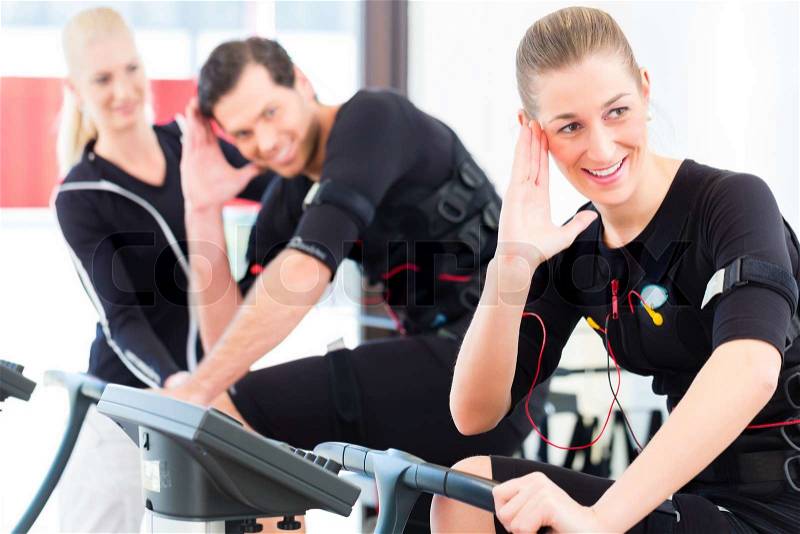Female coach giving man and woman ems electro muscular stimulation exercise , stock photo