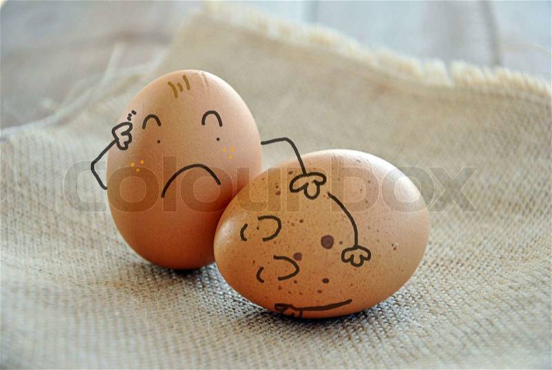 Caricatures of eggs on wooden table and burlap, stock photo