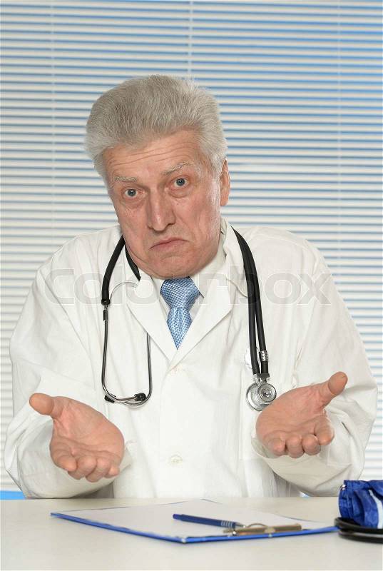 Elderly doctor at a table on a white background, stock photo