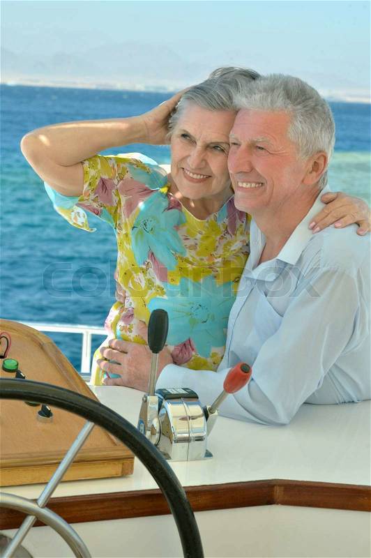 Amusing elderly couple have a ride in a boat on sea, stock photo