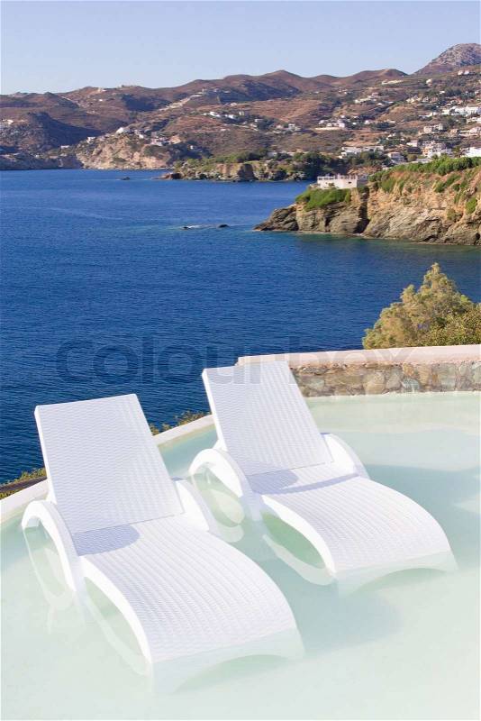 White chairs in pool with beautiful sea view, stock photo