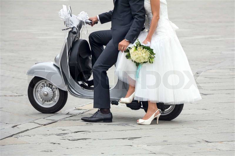 Young newlywed just married, posing on an old gray scooter, stock photo