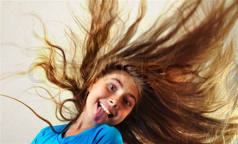 Adorable child with long floating hair sticking her tongue out, stock photo