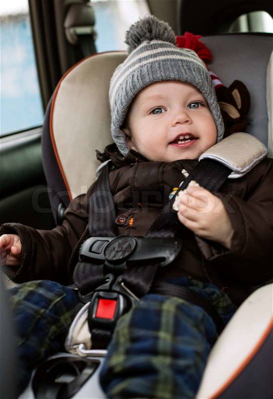 Happy toddler boy sitting in the car seat in the autumn, stock photo