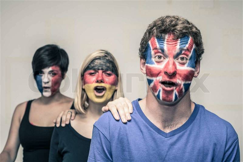 Group of exited people with painted flags on their faces shouting, stock photo