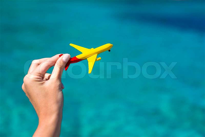 Small homemade plane in a female hand on a background of the sea, stock photo