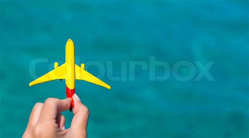 Small homemade plane in a female hand on a background of the sea, stock photo