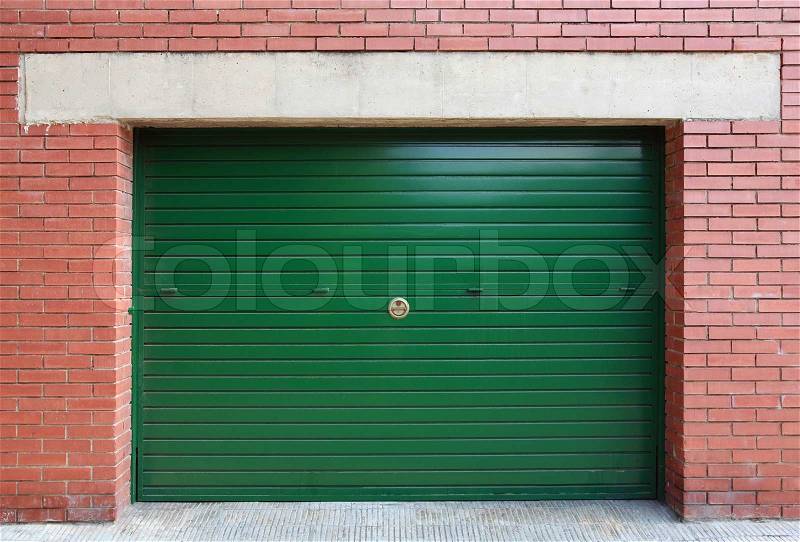 Green metal garage gate in red brick wall, background texture, stock photo