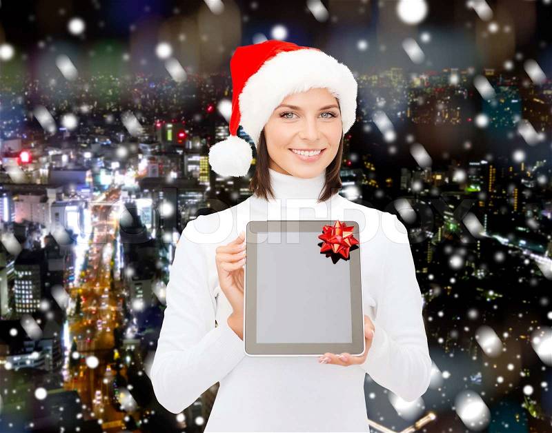 Christmas, technology, present and people concept - smiling woman in santa helper hat with blank screen tablet pc computer over night city background, stock photo