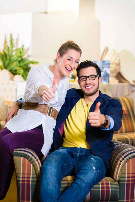 Young couple selecting together armchair in furniture store , stock photo