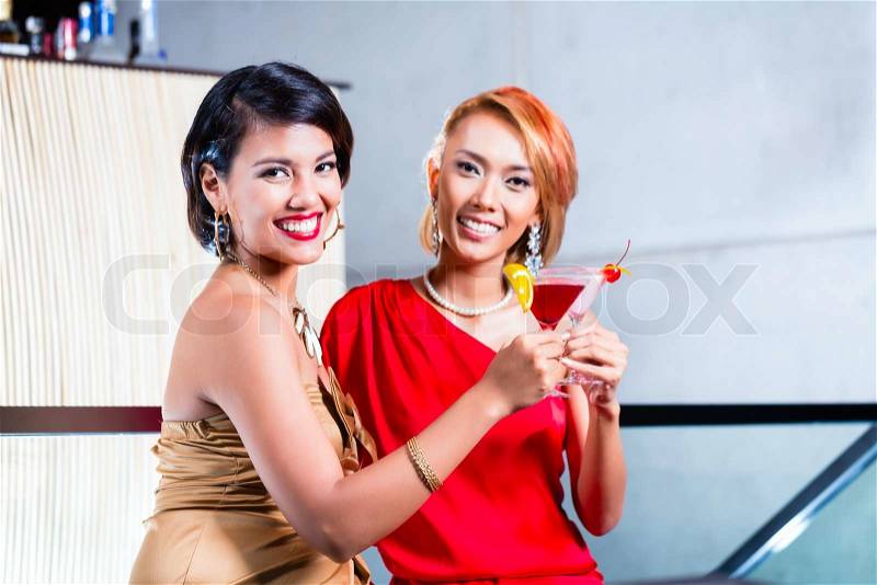 Asian women drinking cocktails in fancy bar, stock photo