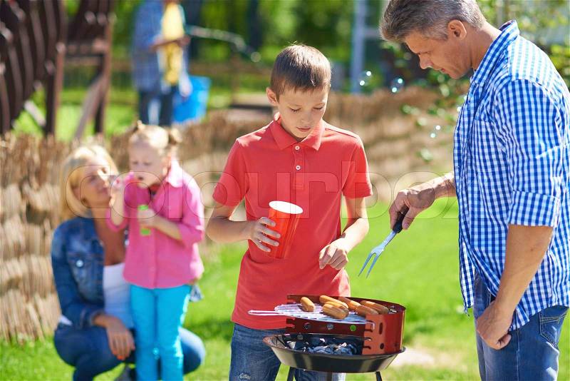 Big family frying sausages on grill, stock photo