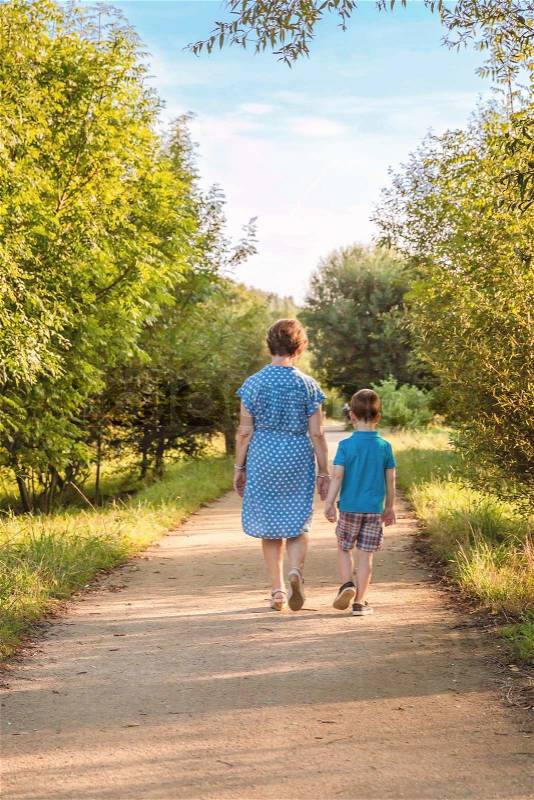 Back view of grandmother and grandchild walking on a nature path, stock photo