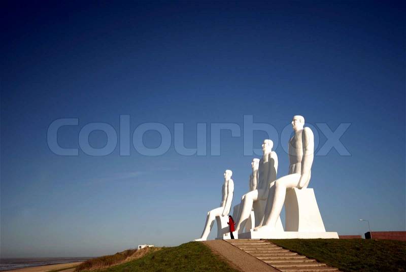 The sculpture ?Man meets the Sea? and one woman visitor. The 4 people is 9 m high and made in white concrete by the Danish artist Svend Wiig Hansen. Esbjerg, Denmark on April 9, 2009, stock photo