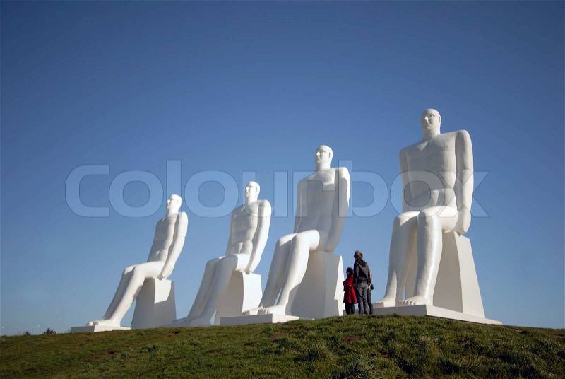 People looking at the sculpture ?Man meets the Sea?. The 4 white figures is 9 m high and made in white concrete by the Danish artist Svend Wiig Hansen. Esbjerg, Denmark on April 9, 2009, stock photo