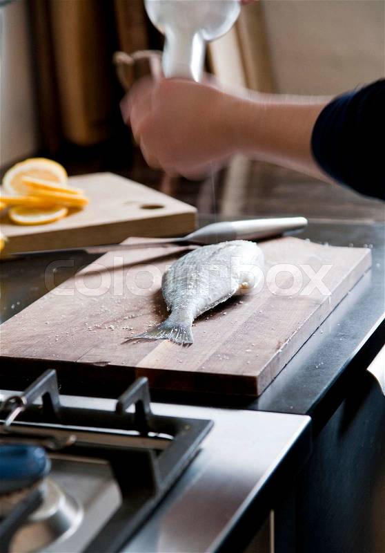 A woman preparing fish in the kitchen, stock photo