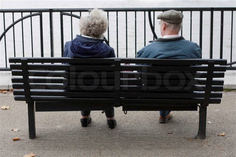 Two elderly people sitting on a bench, stock photo