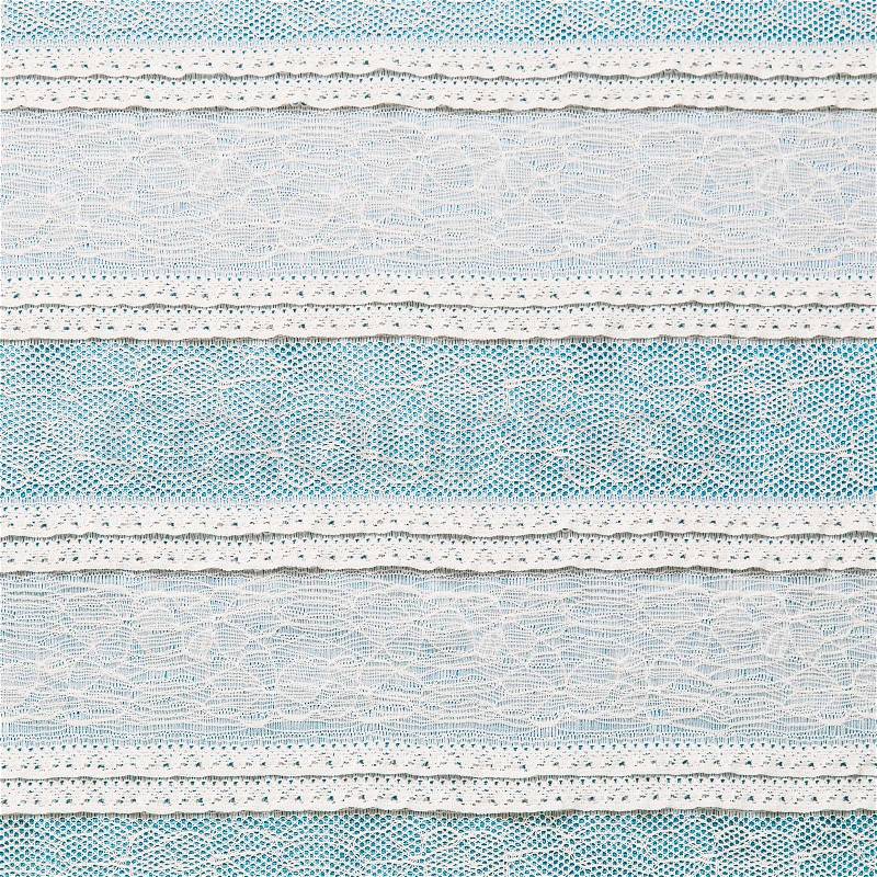 Ivory lace fabric on blue background, stock photo
