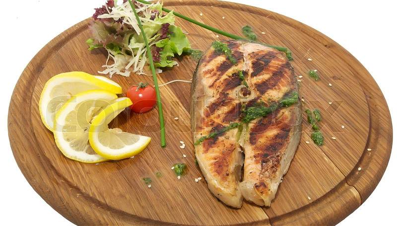 Wooden plate with a piece of fish cooked on the grill, stock photo